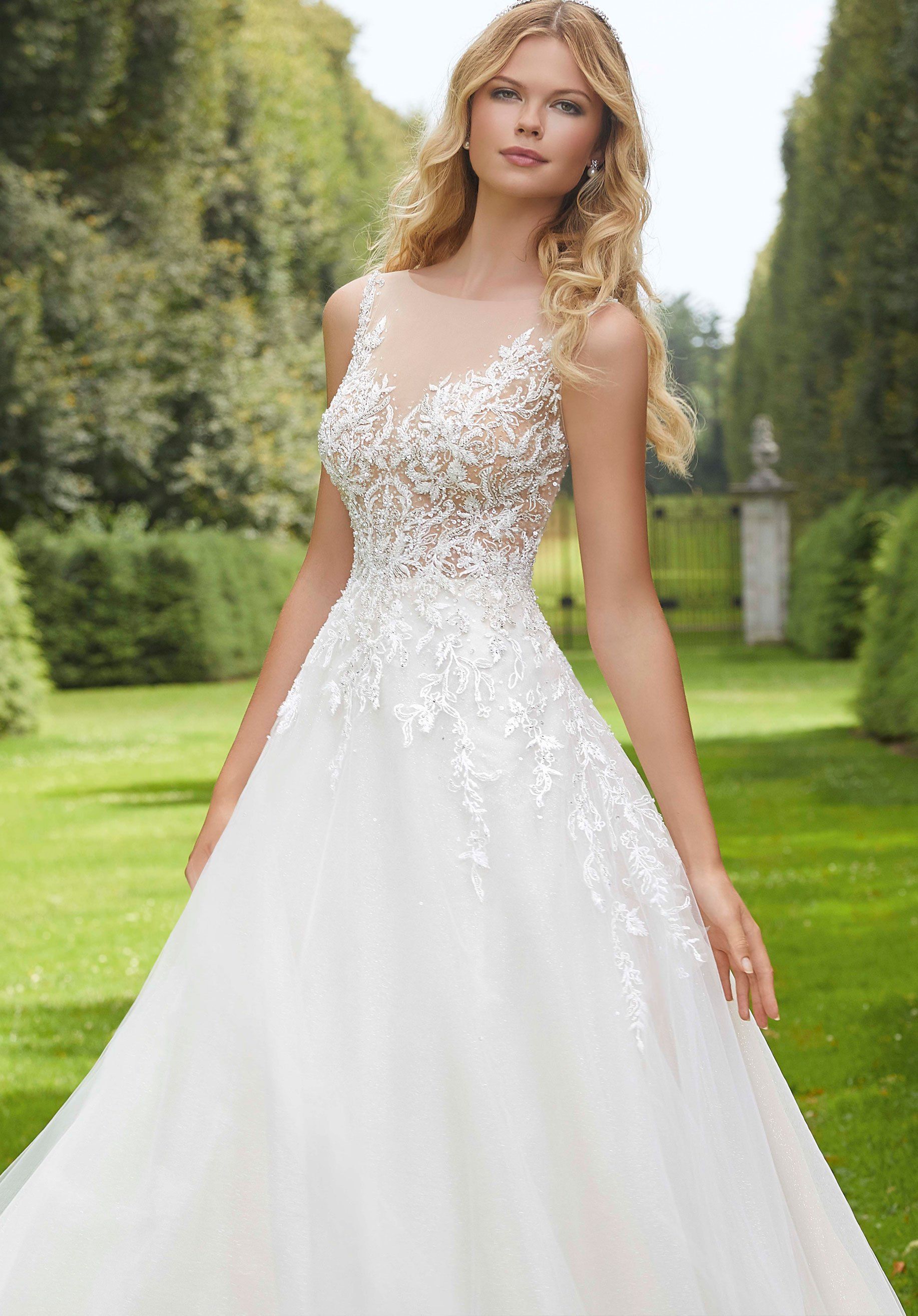 Eine Frau in einem weißen Brautkleid steht in einem Park.