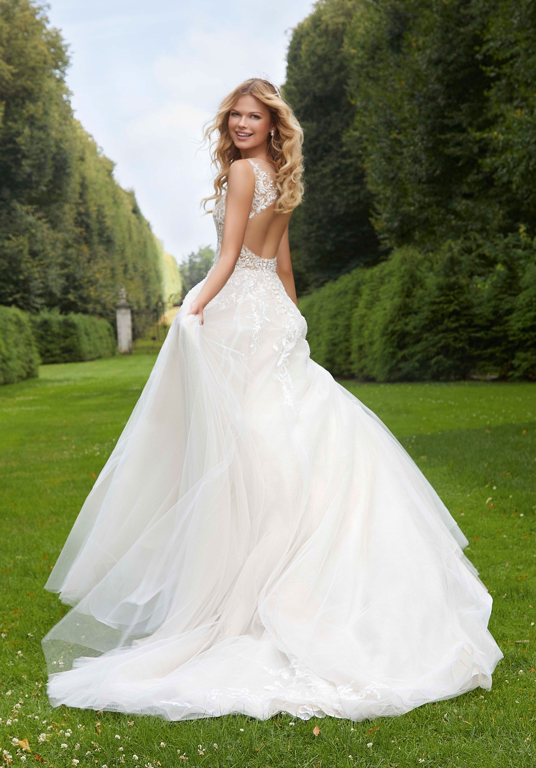 Eine Frau in einem weißen Brautkleid steht im Gras.