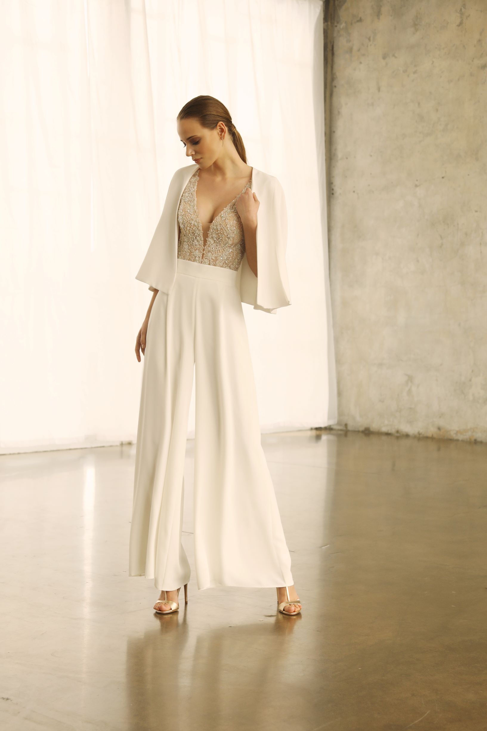 Eine Frau in einem weißen Kleid und Overall steht in einem Raum.