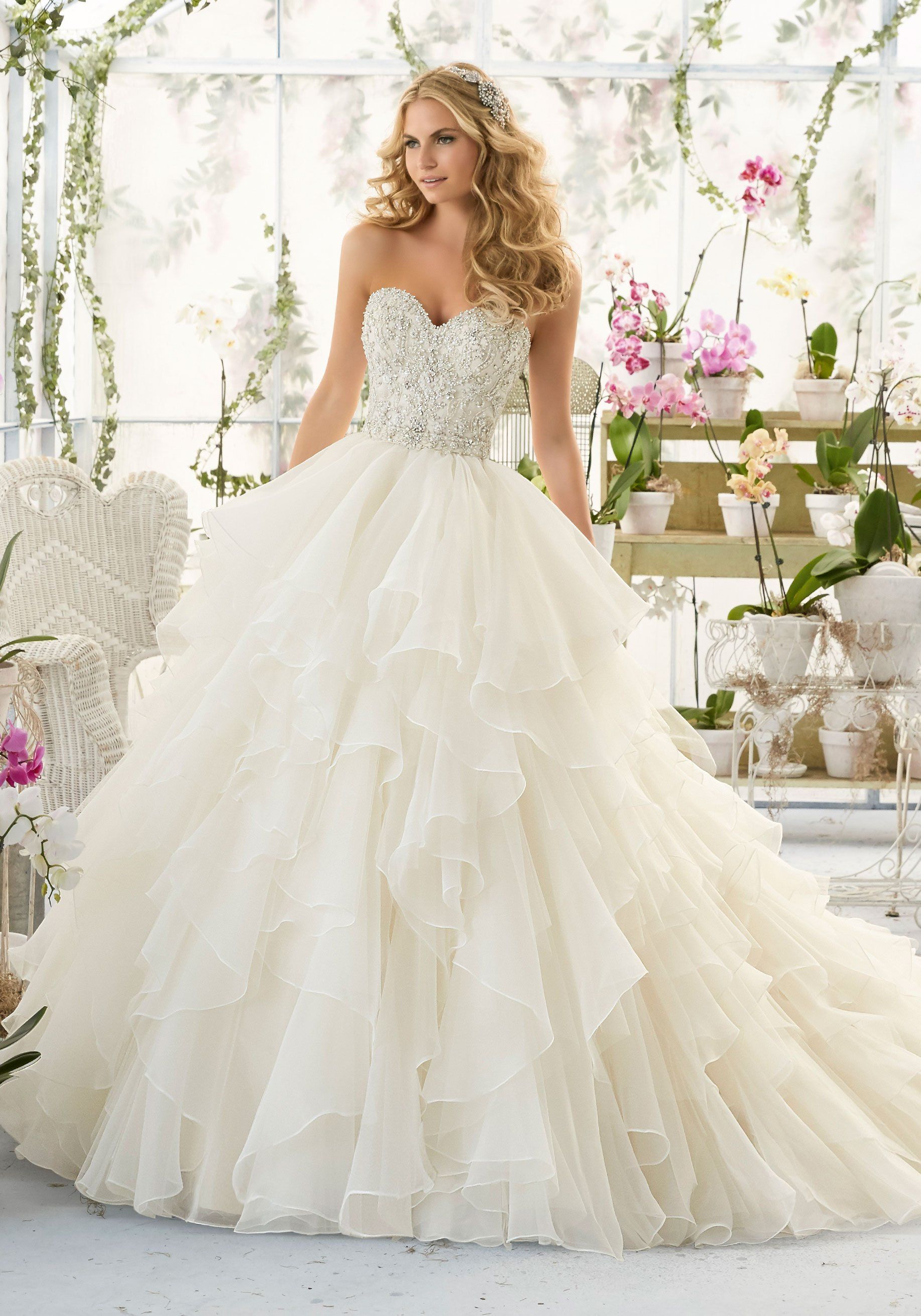 Eine Frau in einem weißen Brautkleid steht vor Blumen.
