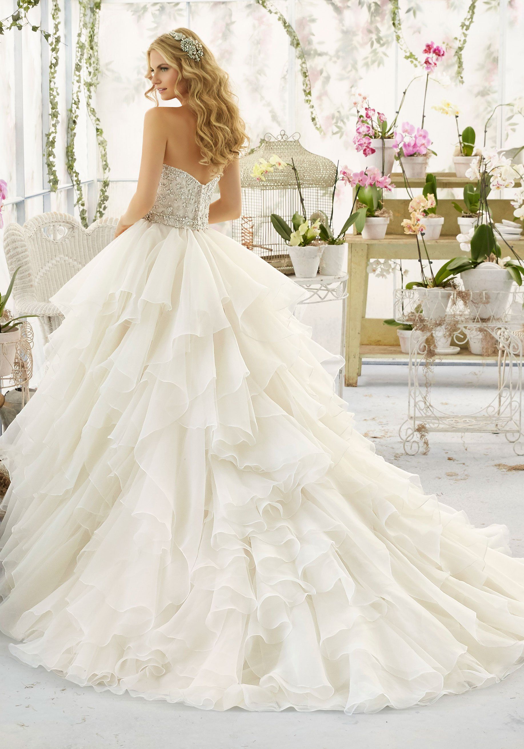 Eine Frau trägt ein weißes Brautkleid mit langer Schleppe.