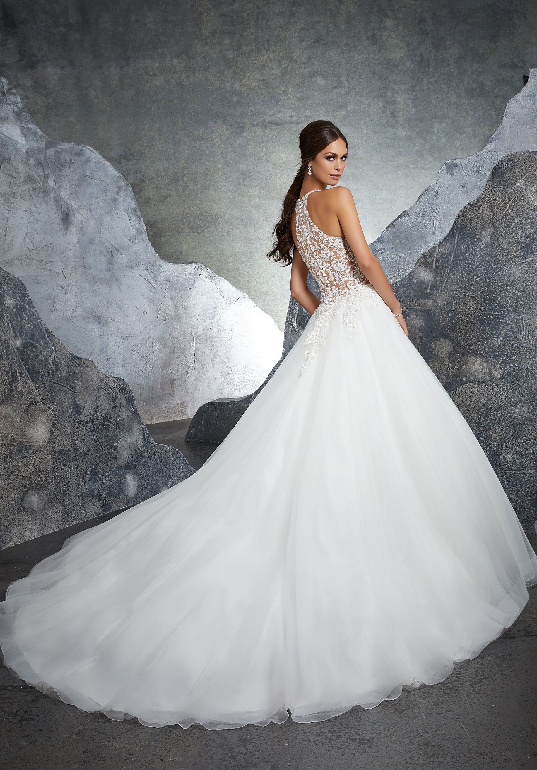 Eine Frau trägt ein weißes Brautkleid mit langer Schleppe.