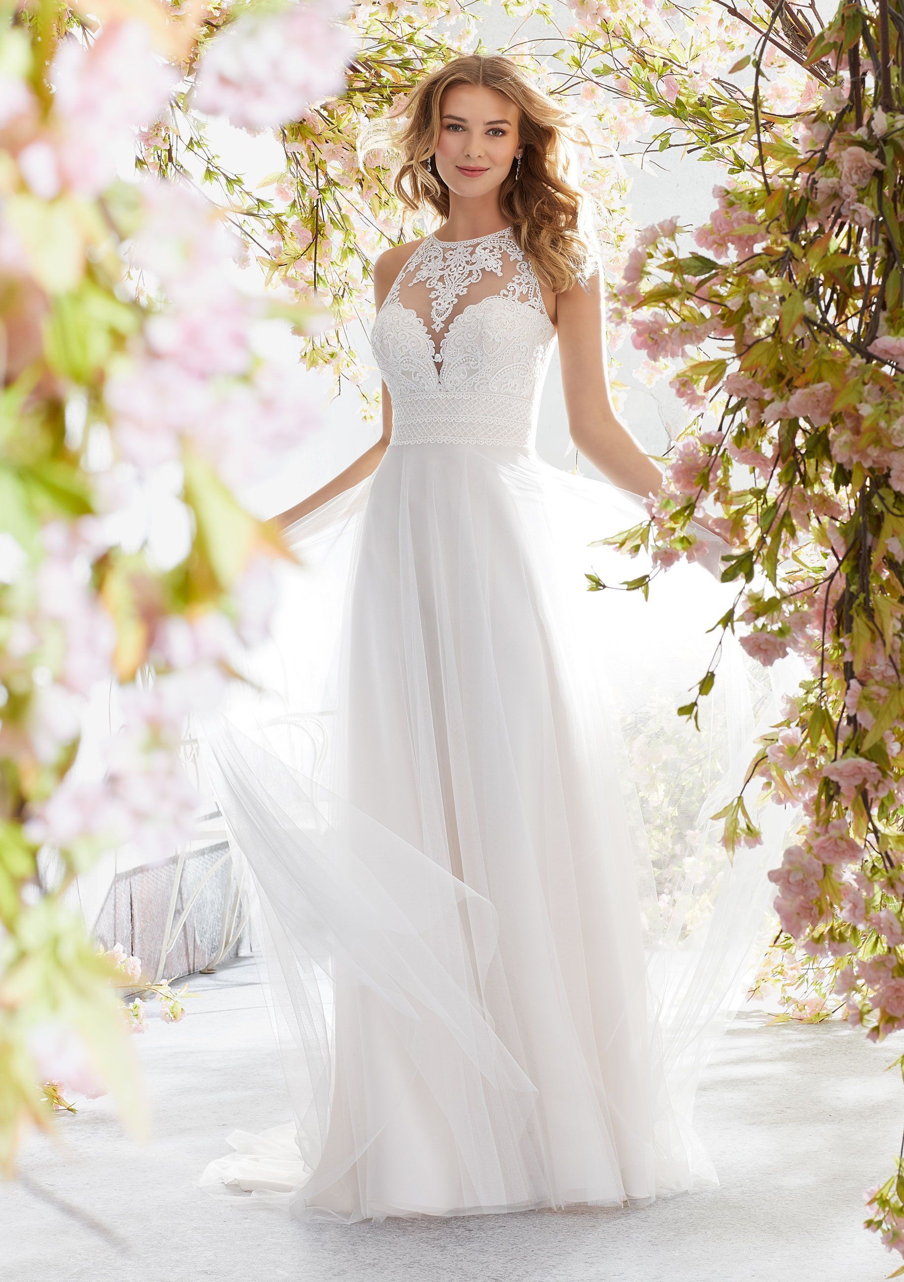 Eine Frau in einem weißen Brautkleid steht vor Blumen.