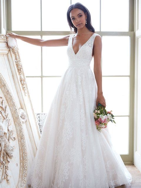 Eine Frau in einem weißen Brautkleid hält einen Blumenstrauß.