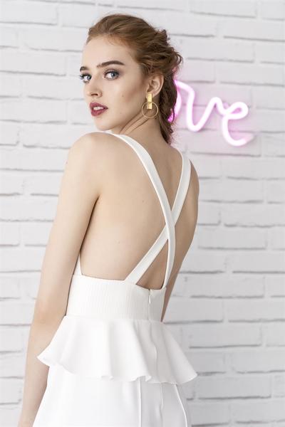 Eine Frau in einem weißen Kleid steht vor einem Neonschild mit der Aufschrift „Liebe“