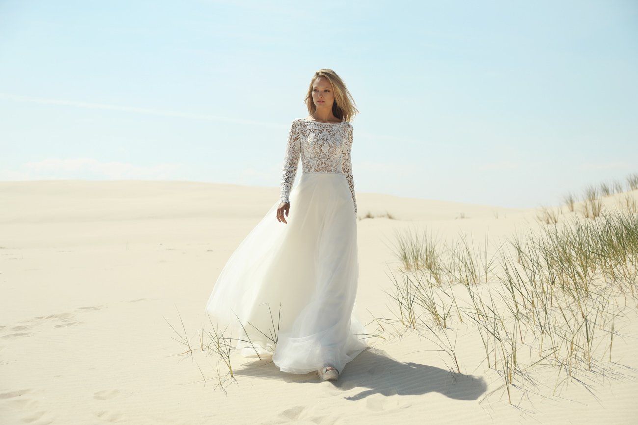 Eine Frau in einem Brautkleid läuft im Sand.