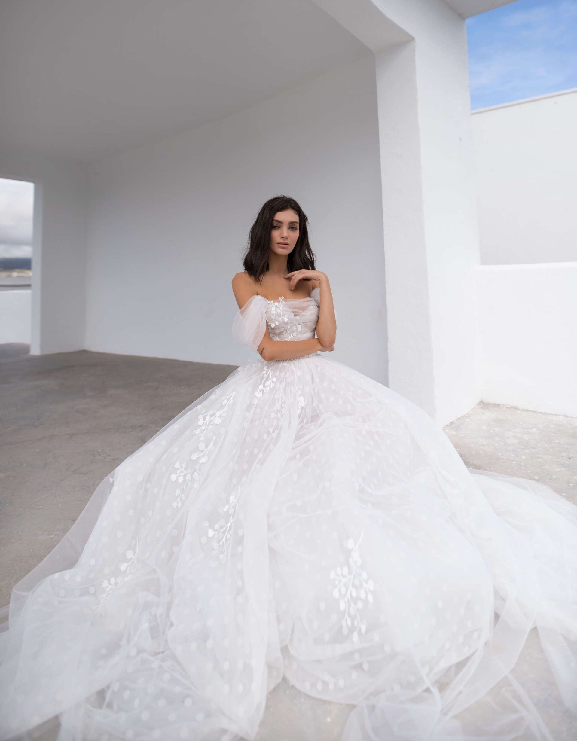 Eine Frau in einem weißen Brautkleid steht vor einem weißen Gebäude.