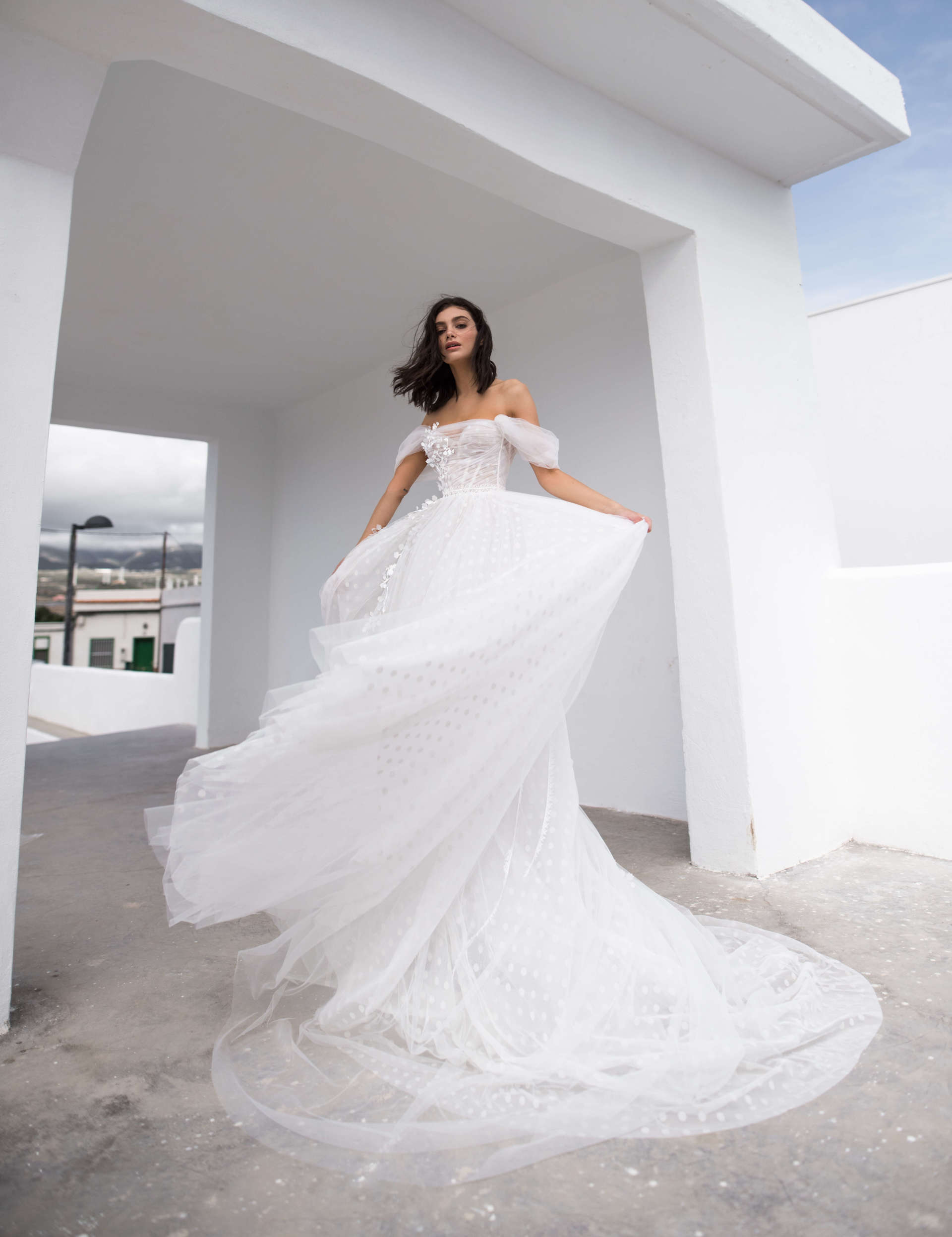 Eine Frau in einem weißen Brautkleid steht vor einem weißen Gebäude.