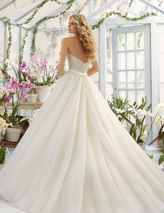 Eine Frau in einem Brautkleid steht in einem Gewächshaus, umgeben von Blumen