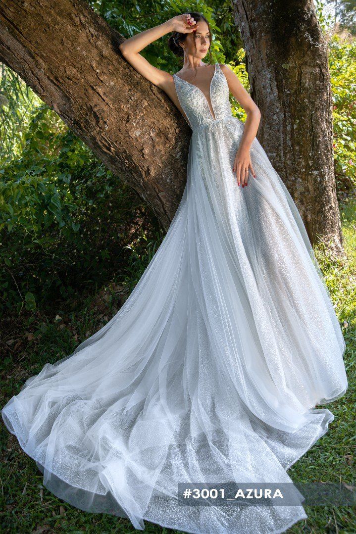 Eine Frau in einem weißen Brautkleid lehnt an einem Baum.