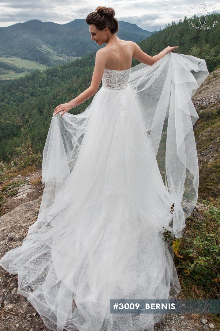 Eine Frau in einem Brautkleid steht auf einem Berggipfel.