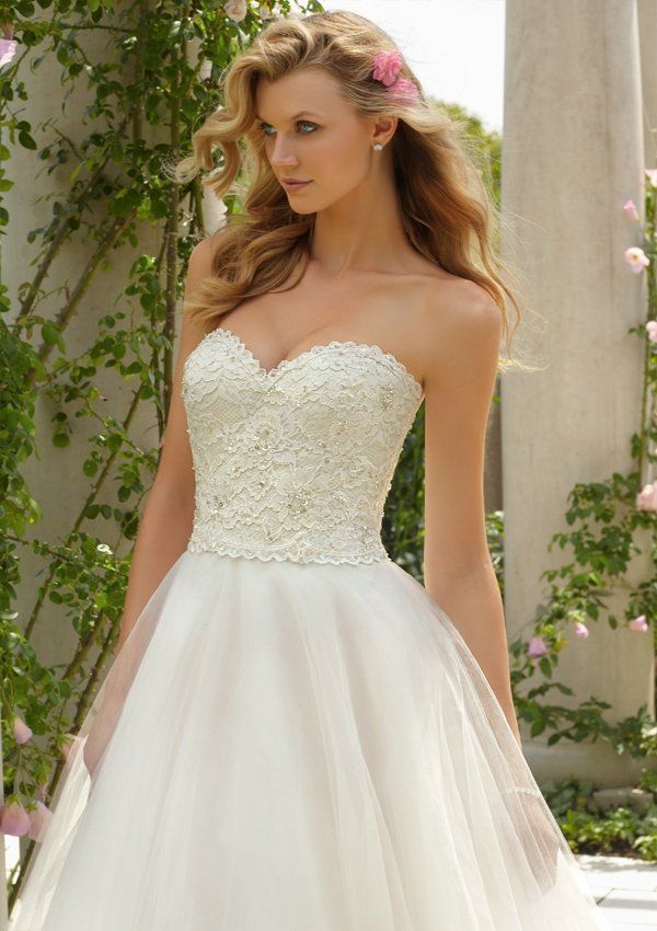 Eine Frau trägt ein weißes Brautkleid und hat eine Blume im Haar.
