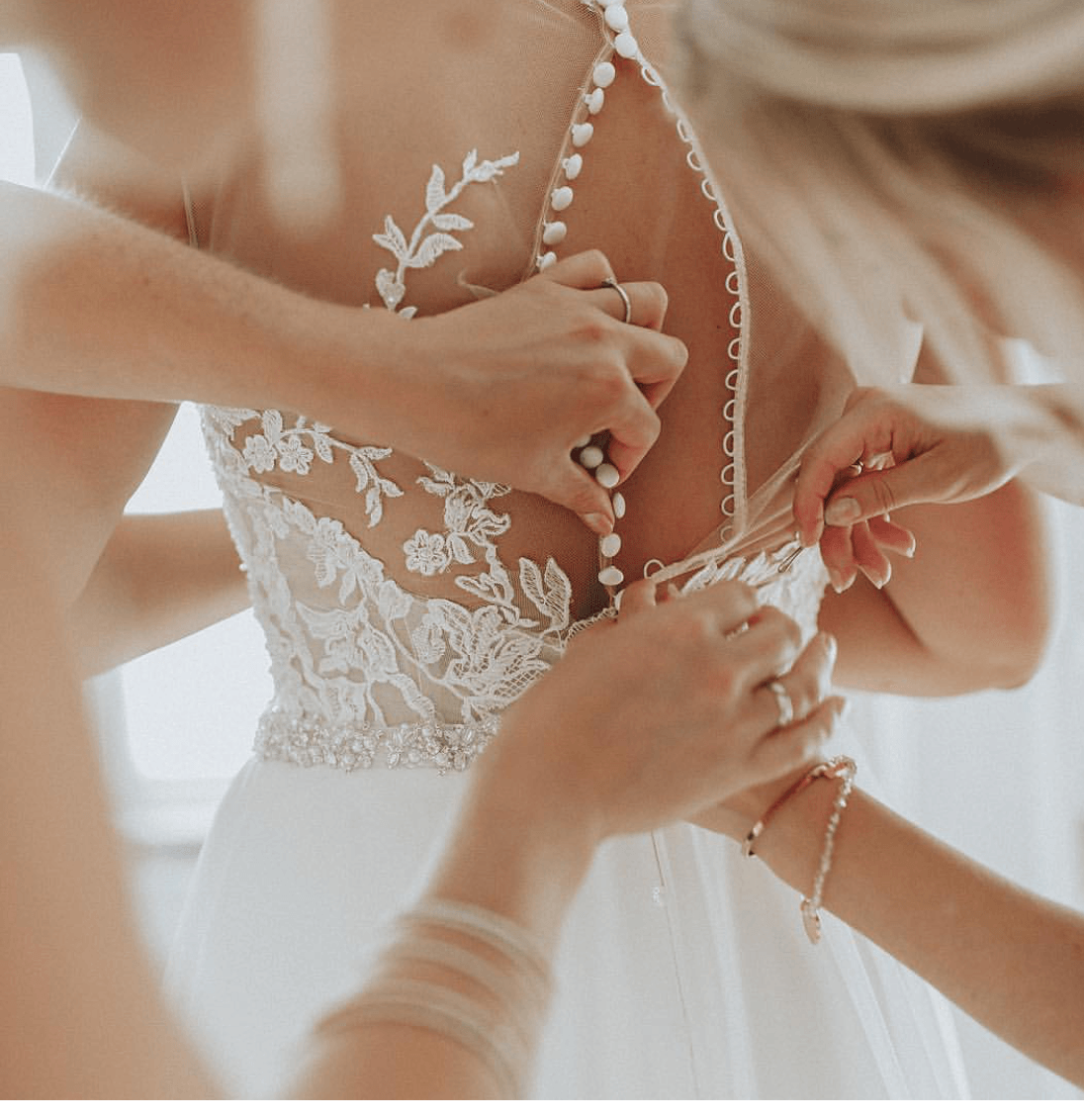 Eine Frau hilft einer Braut mit ihrem Hochzeitskleid.