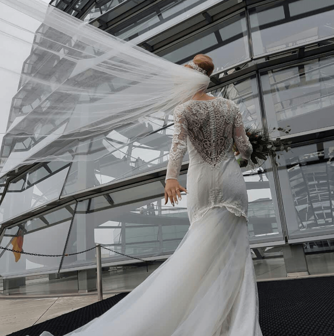Eine Frau in einem Brautkleid geht vor einem Gebäude