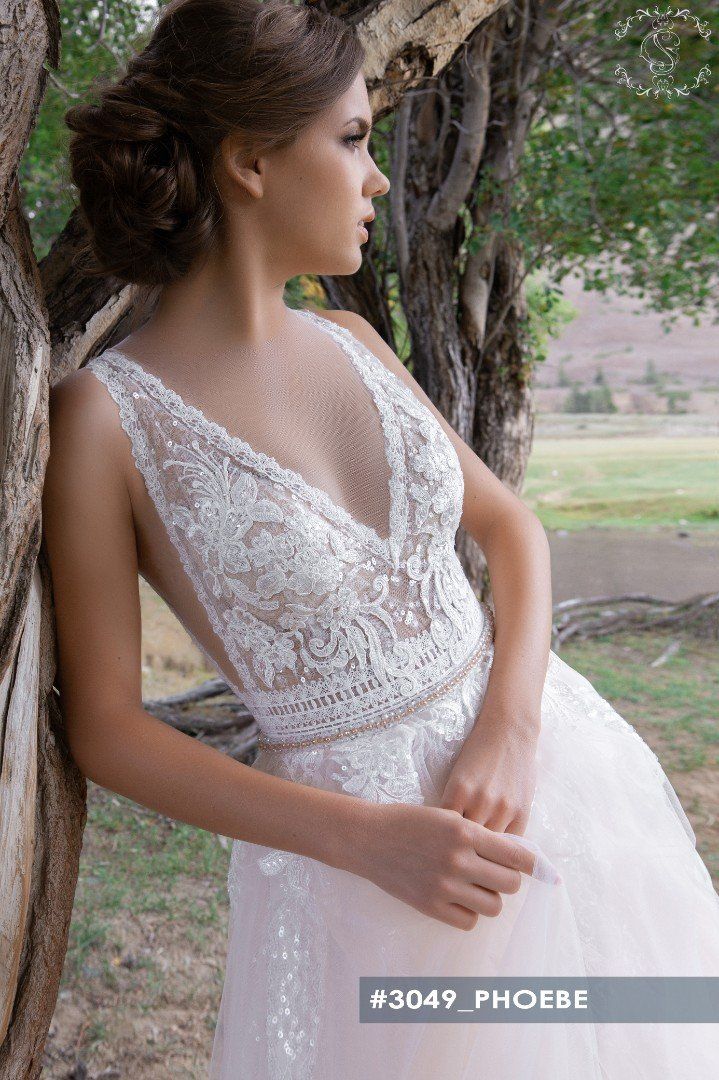 Eine Frau in einem Brautkleid lehnt an einem Baum.