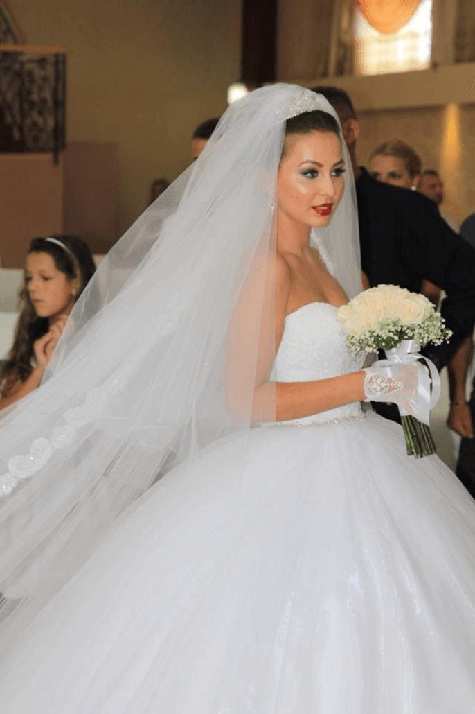 Eine Braut in einem weißen Brautkleid hält einen Blumenstrauß