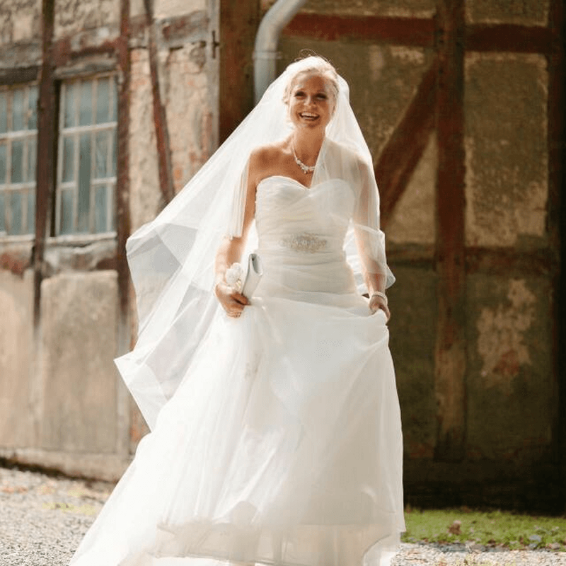 Eine Braut in einem weißen Kleid und Schleier steht vor einem Gebäude