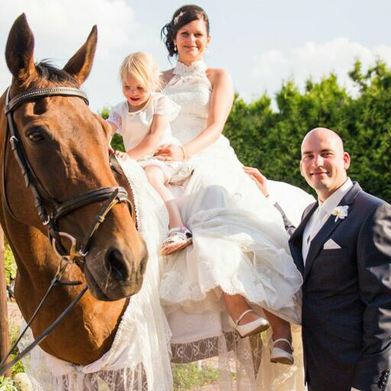 Eine Braut und ein Bräutigam posieren für ein Foto mit einem Pferd