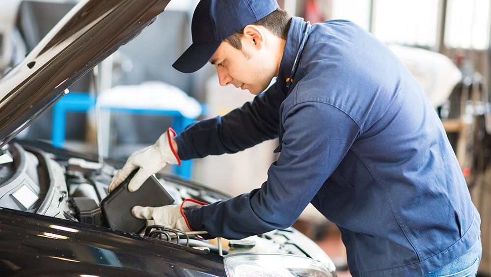 Brake Repairs — Man Putting Engine Oil in Gallatin County, MT