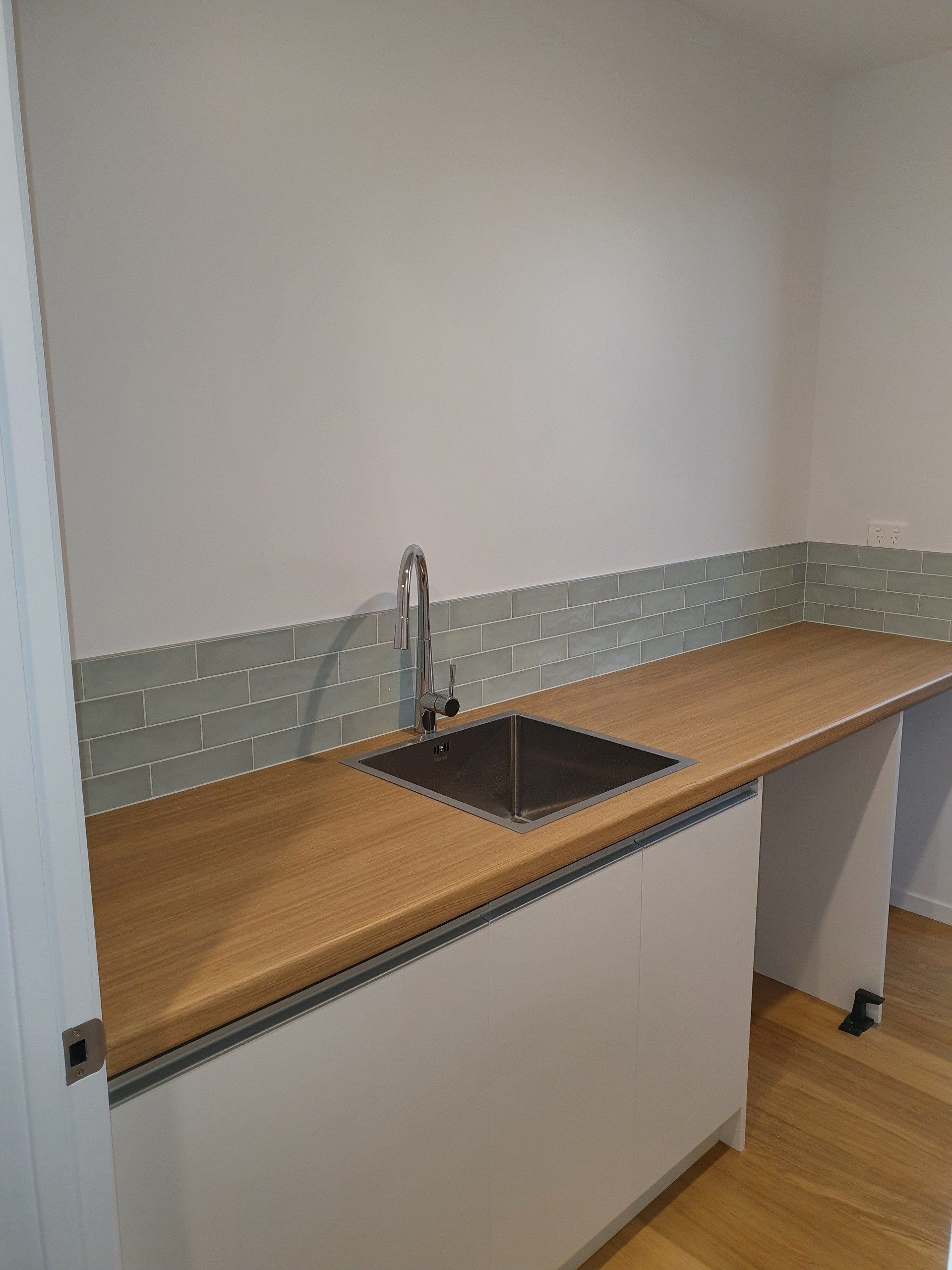 A kitchen with a sink and a wooden counter top.
