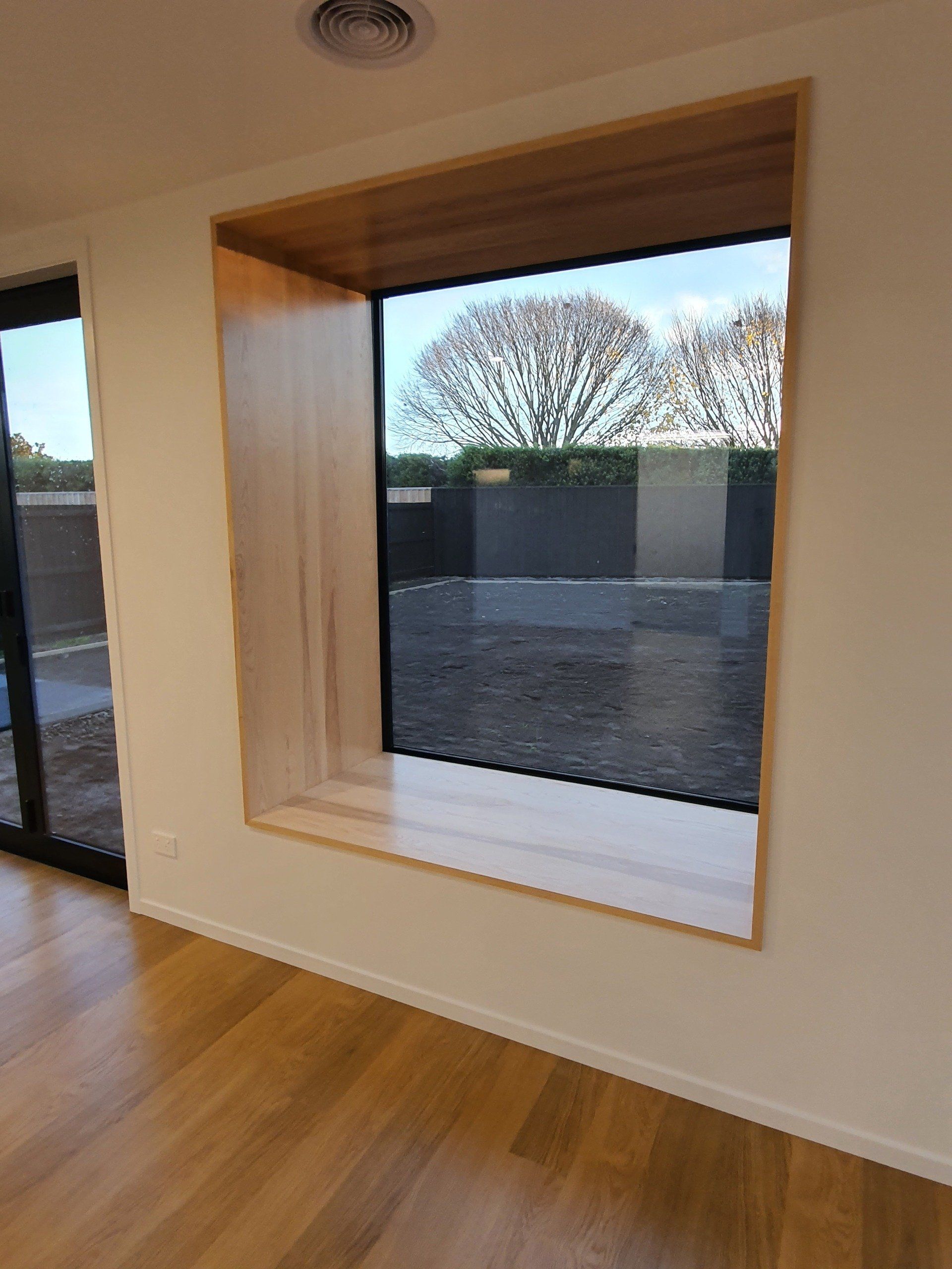 An empty room with a window and a sliding glass door.
