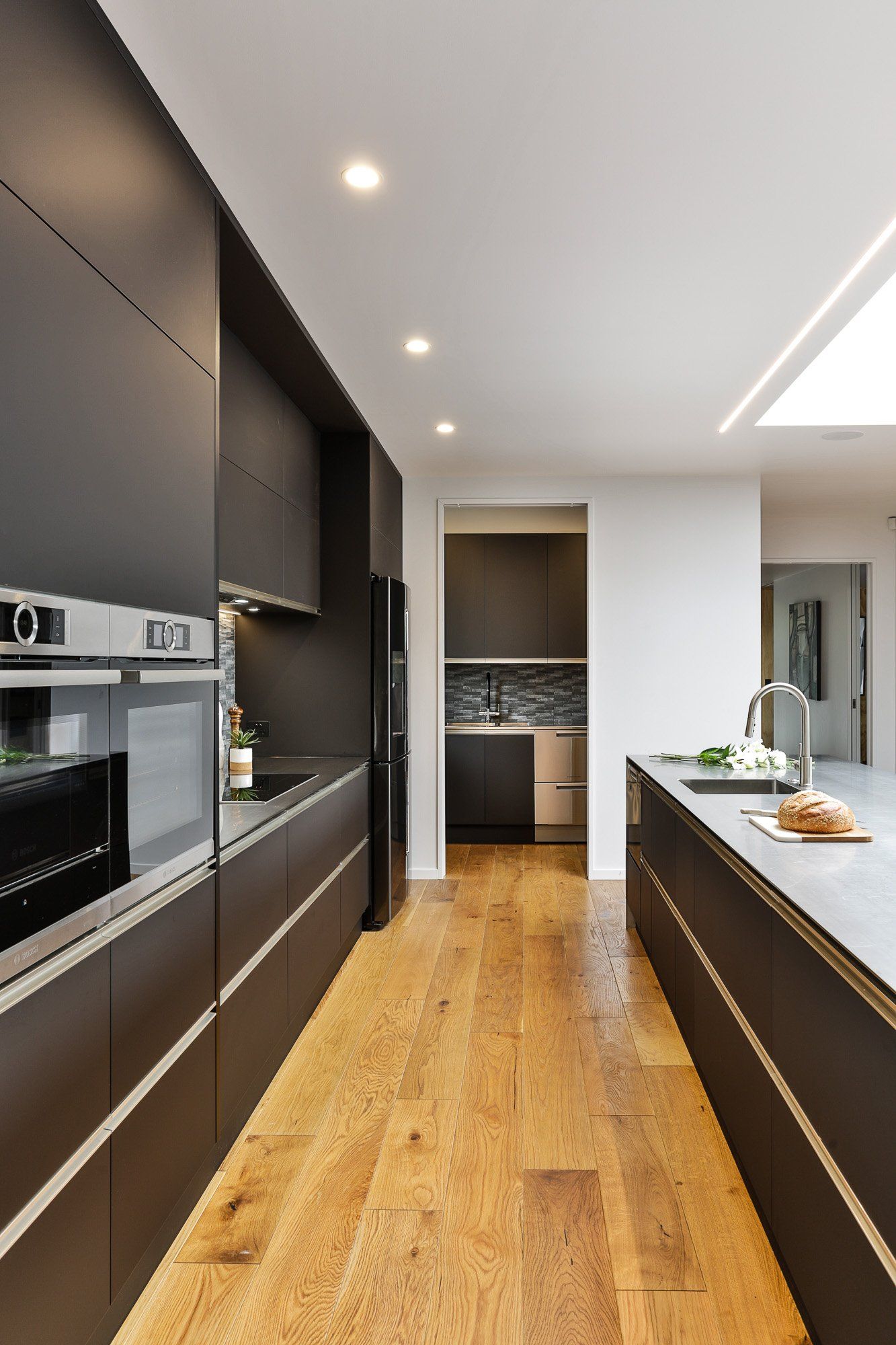 A kitchen with black cabinets and wooden floors