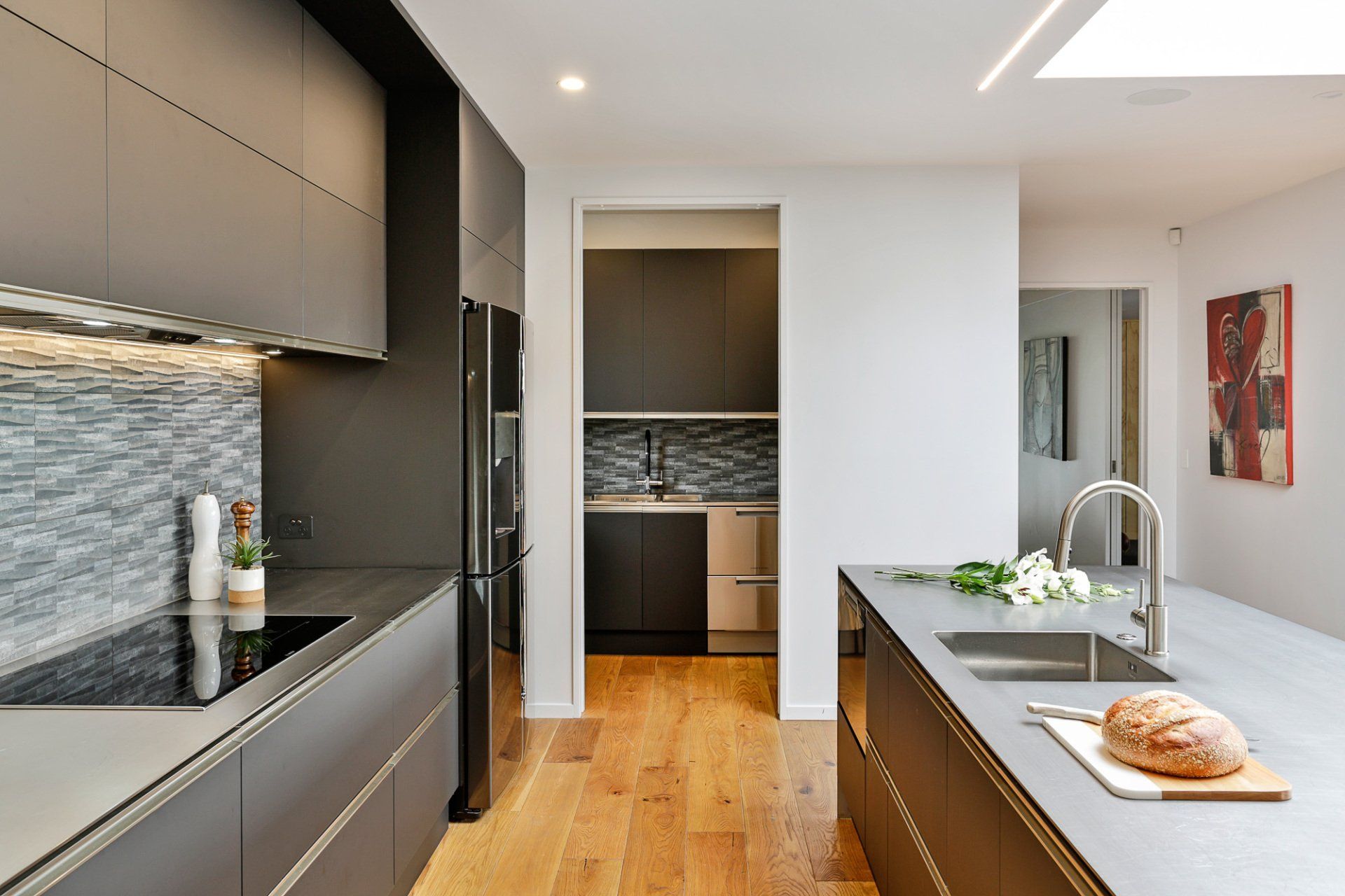 A kitchen with a bread loaf on a cutting board and a sink.