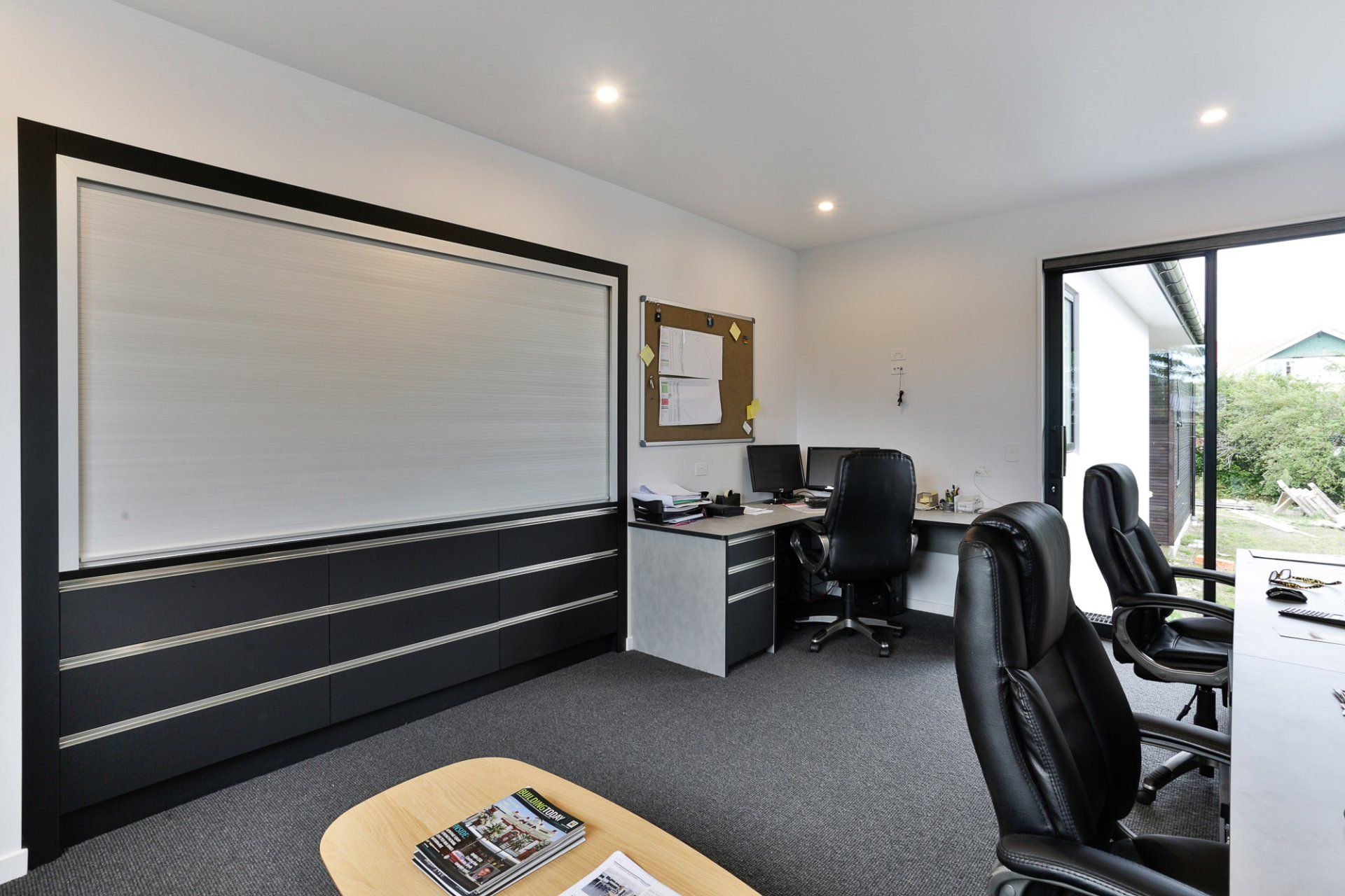 A room with a desk , chairs , a coffee table and a whiteboard.