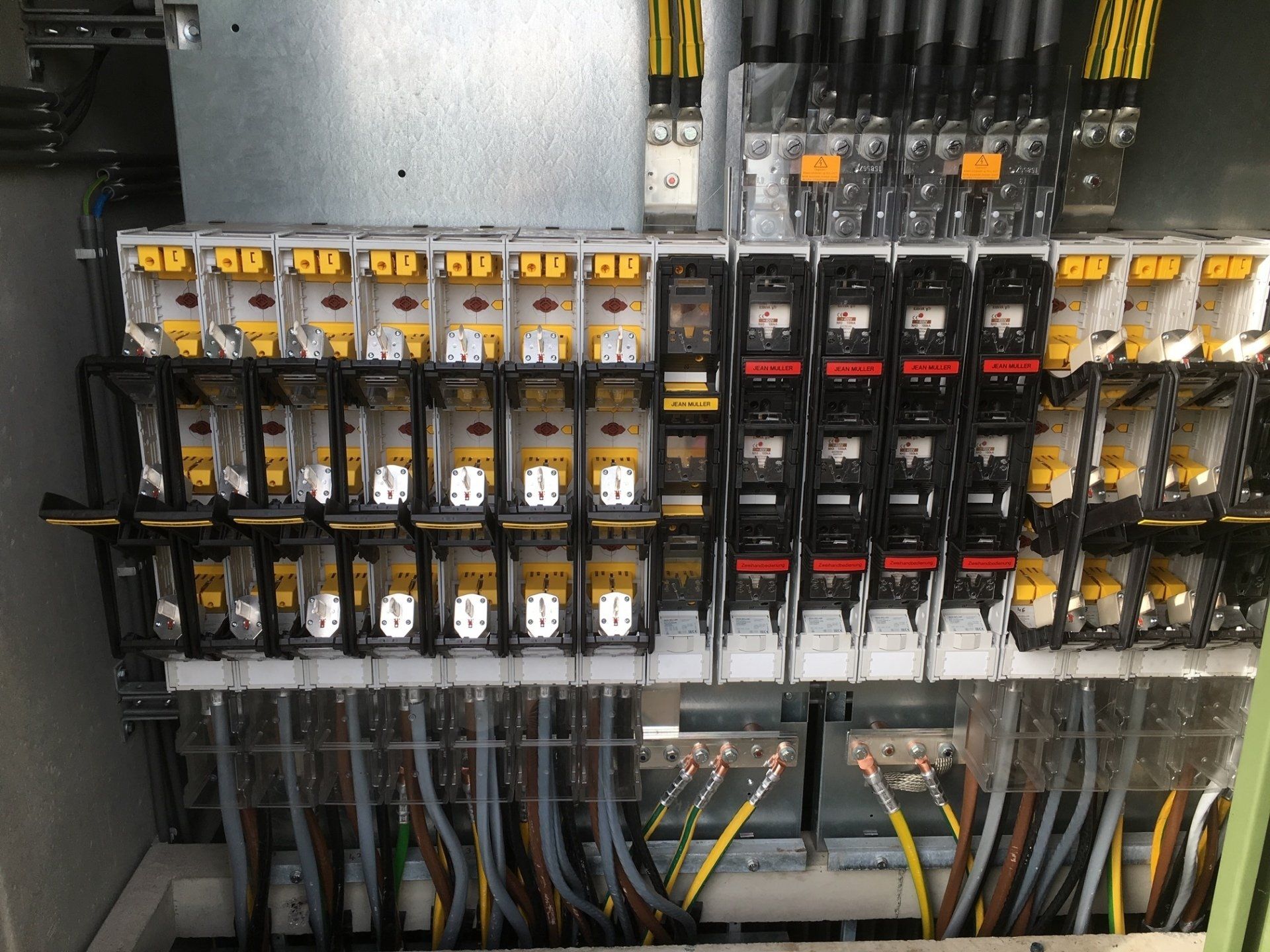 Elektrisch verdeelpaneel met een rij stroomonderbrekers en draadverbindingen, ondergebracht in een metalen behuizing.