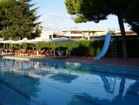 Piscina con scivolo e sedie ombreggiate da un gazebo