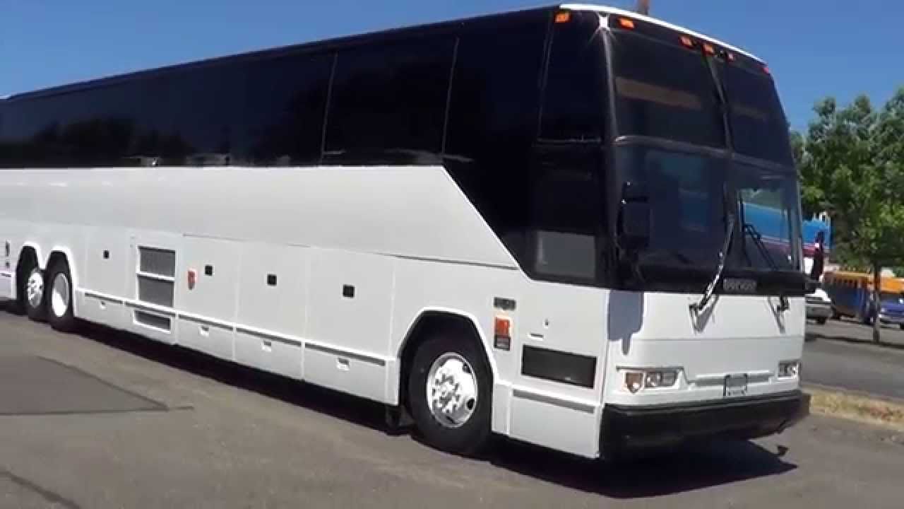 a white coach bus is parked on the side of the road .