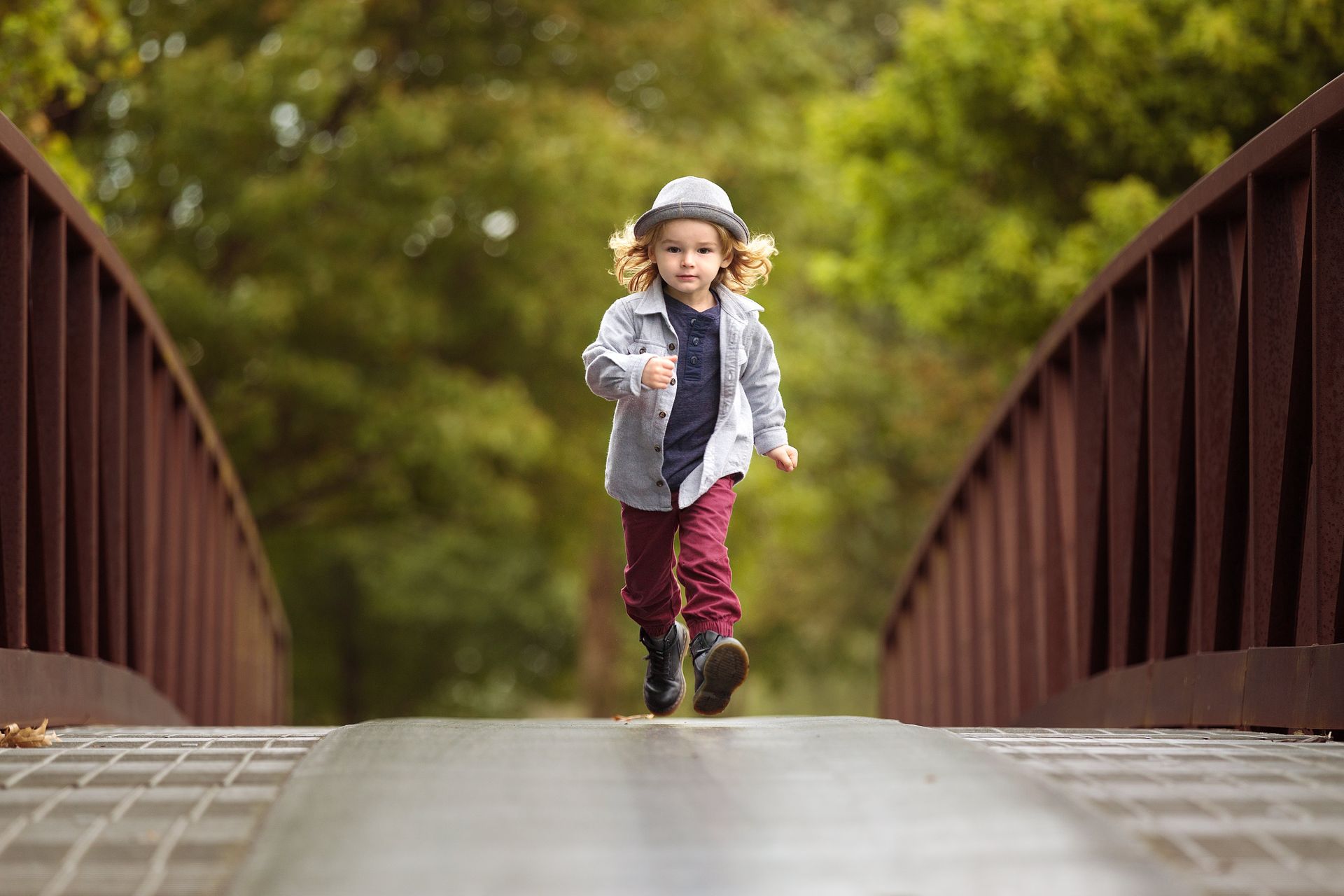 A little girl is running across a bridge.