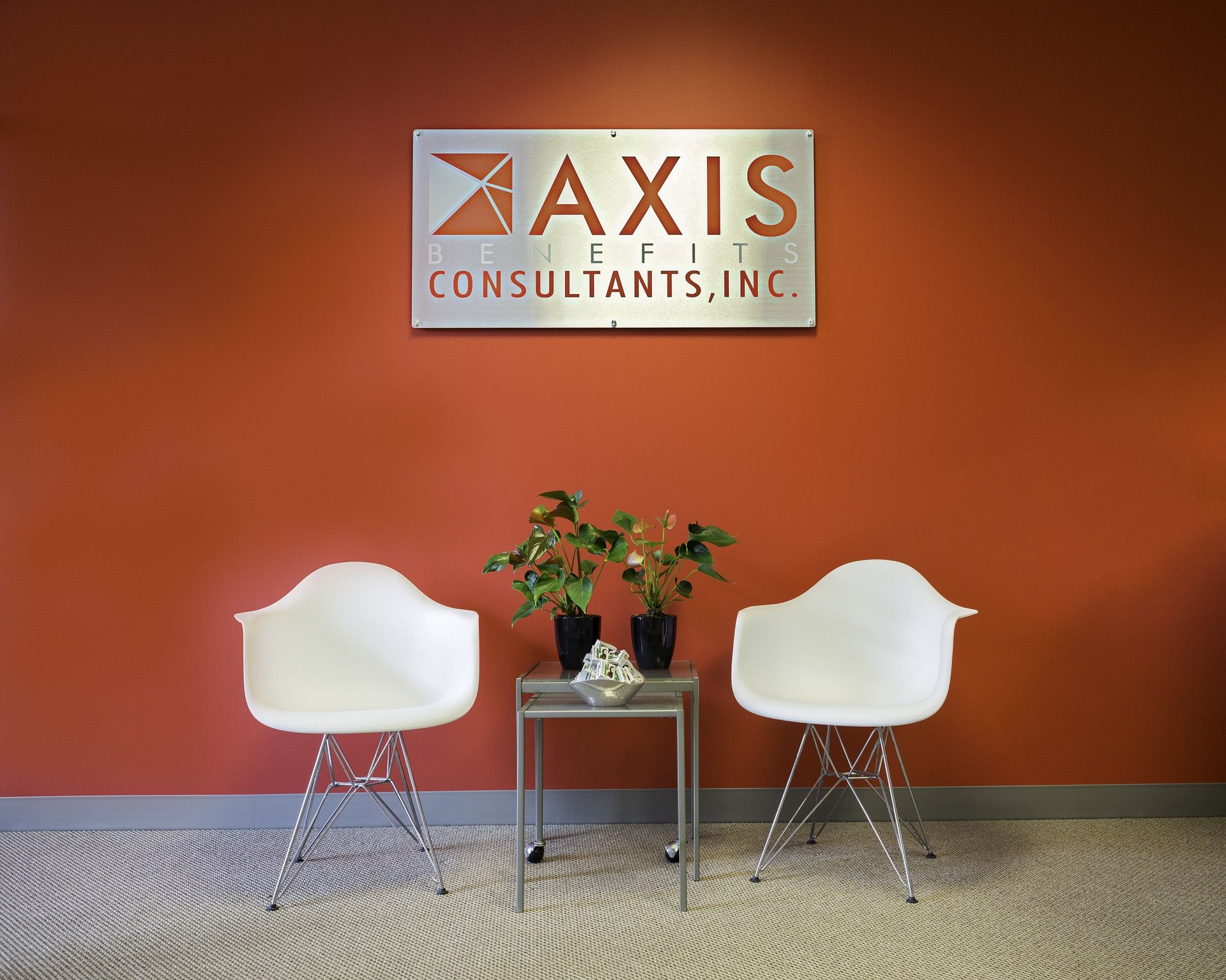 Two white chairs are sitting in front of a sign that says axis