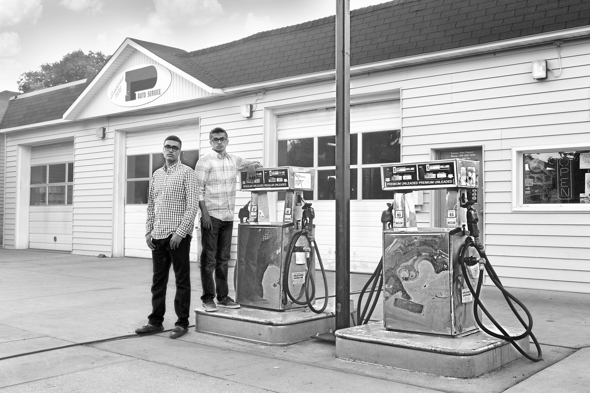 Two men are standing in front of a gas station.