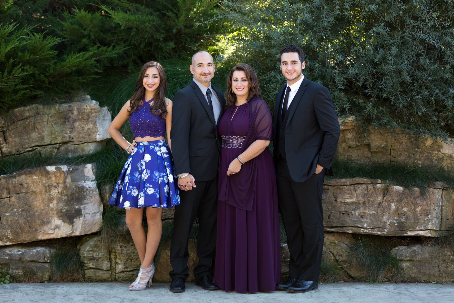 A family is posing for a picture in front of a stone wall.