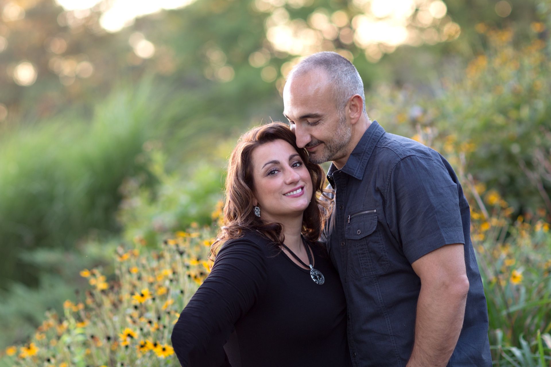 A man and a woman are standing next to each other in a field of flowers.