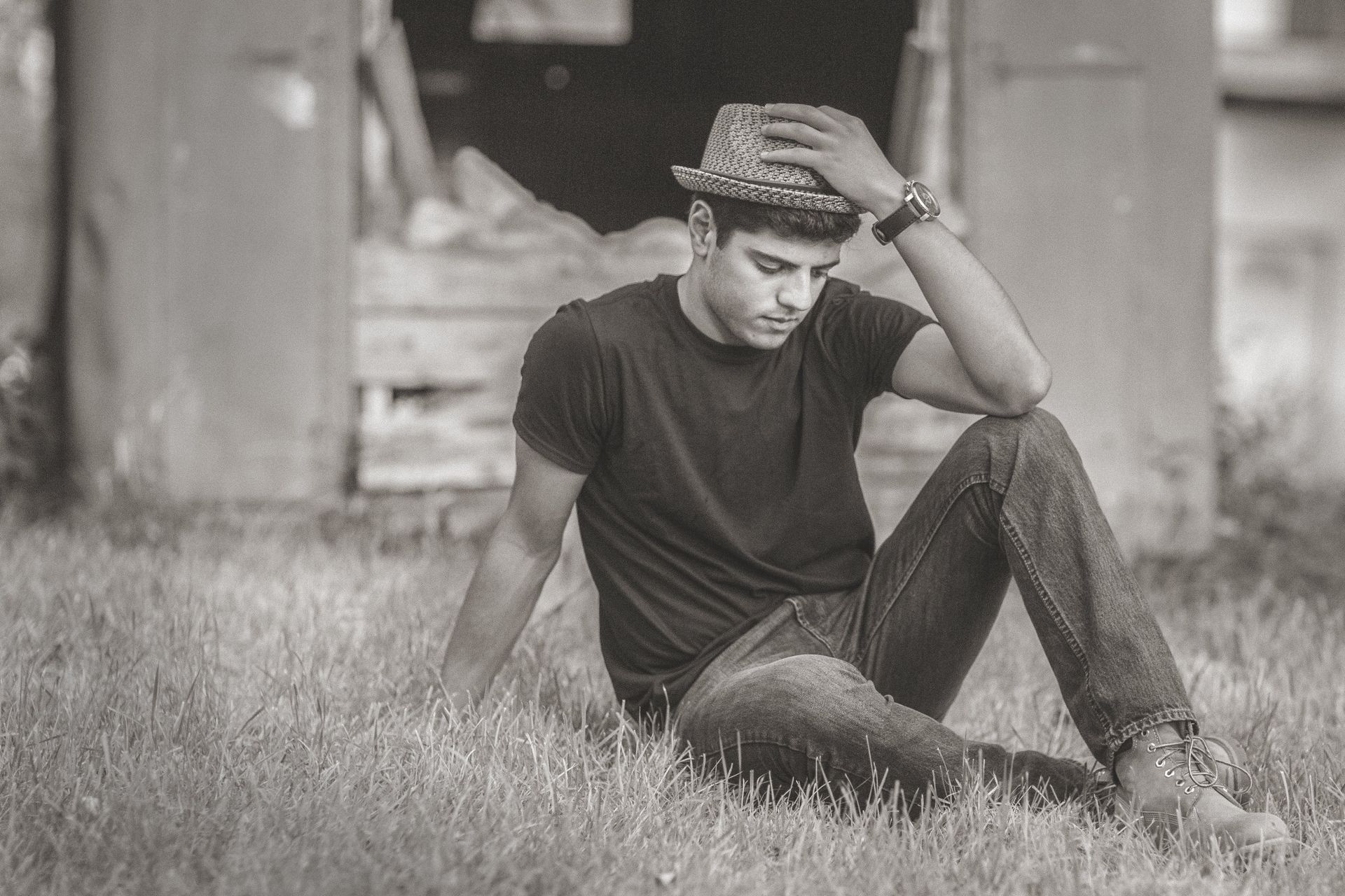 A man wearing a hat is sitting in the grass.