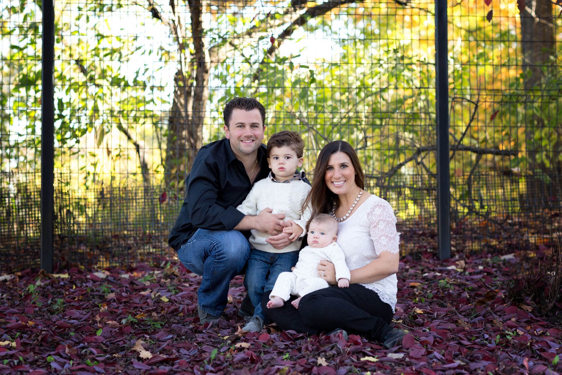A family is posing for a picture in front of a fence.