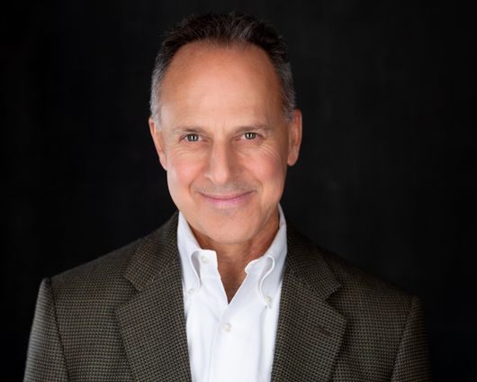 A man in a suit and white shirt is smiling for the camera.