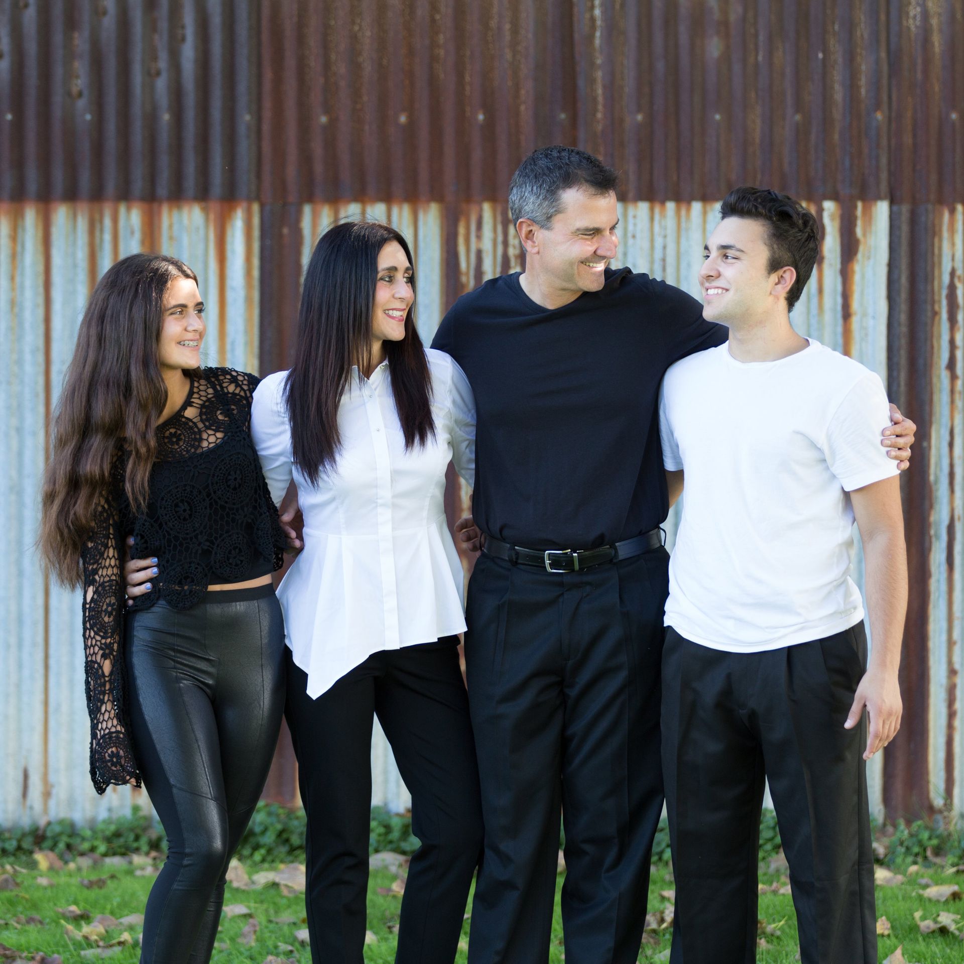 A group of people posing for a picture in front of a rusty wall
