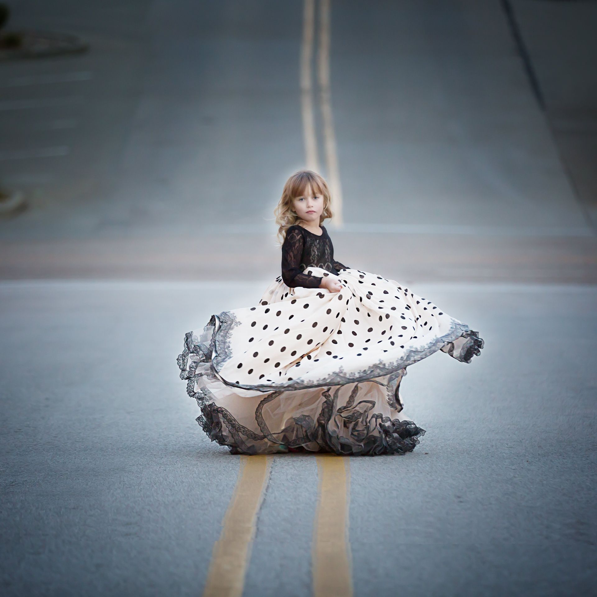 A little girl in a polka dot dress is sitting on a rock