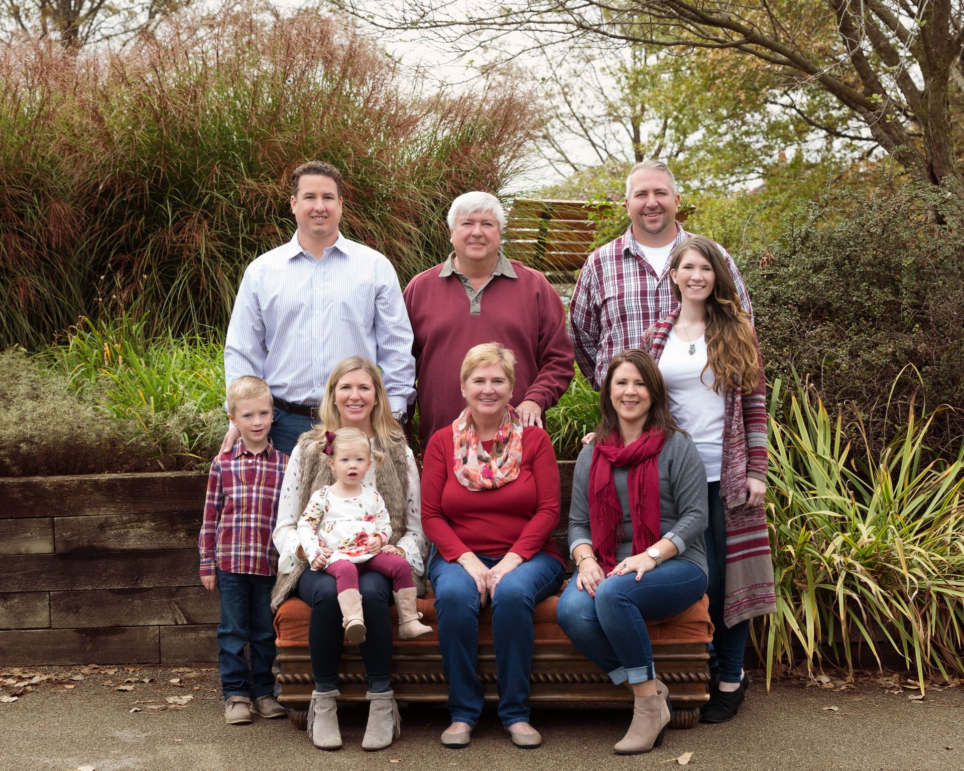 A large family is posing for a picture while sitting on a bench.