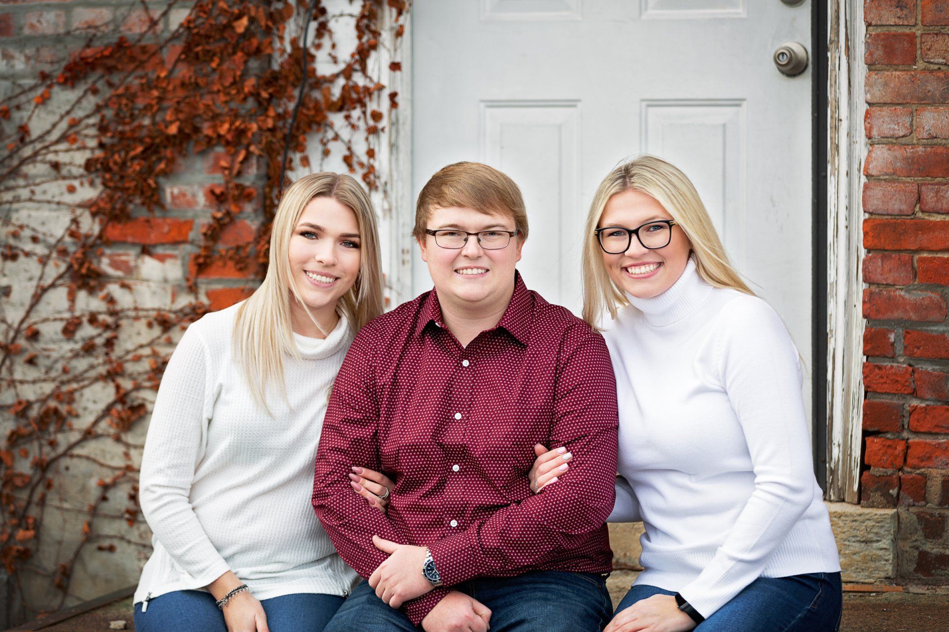 Three people are posing for a picture in front of a white door.