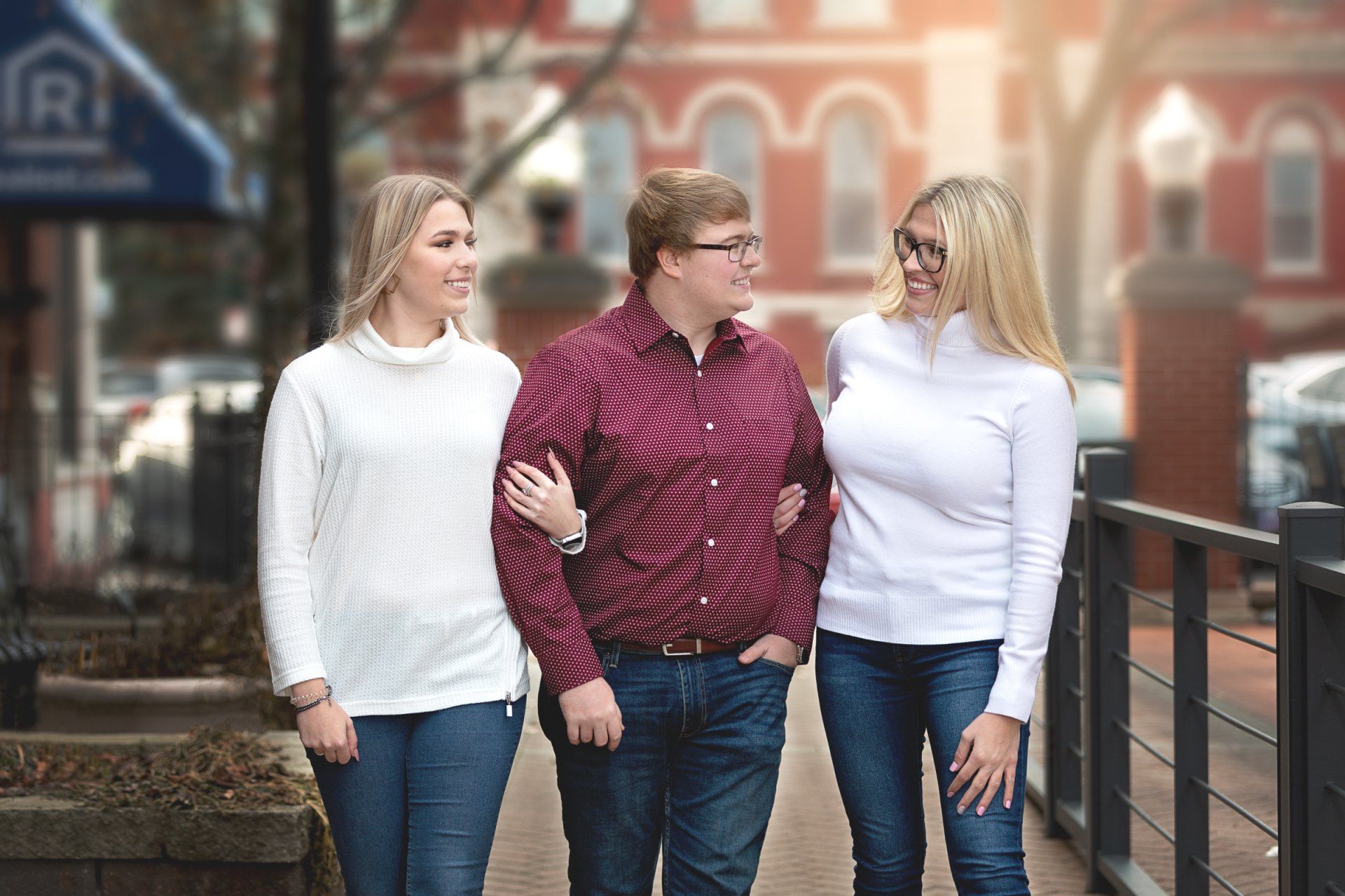A man and two women are walking down a sidewalk.