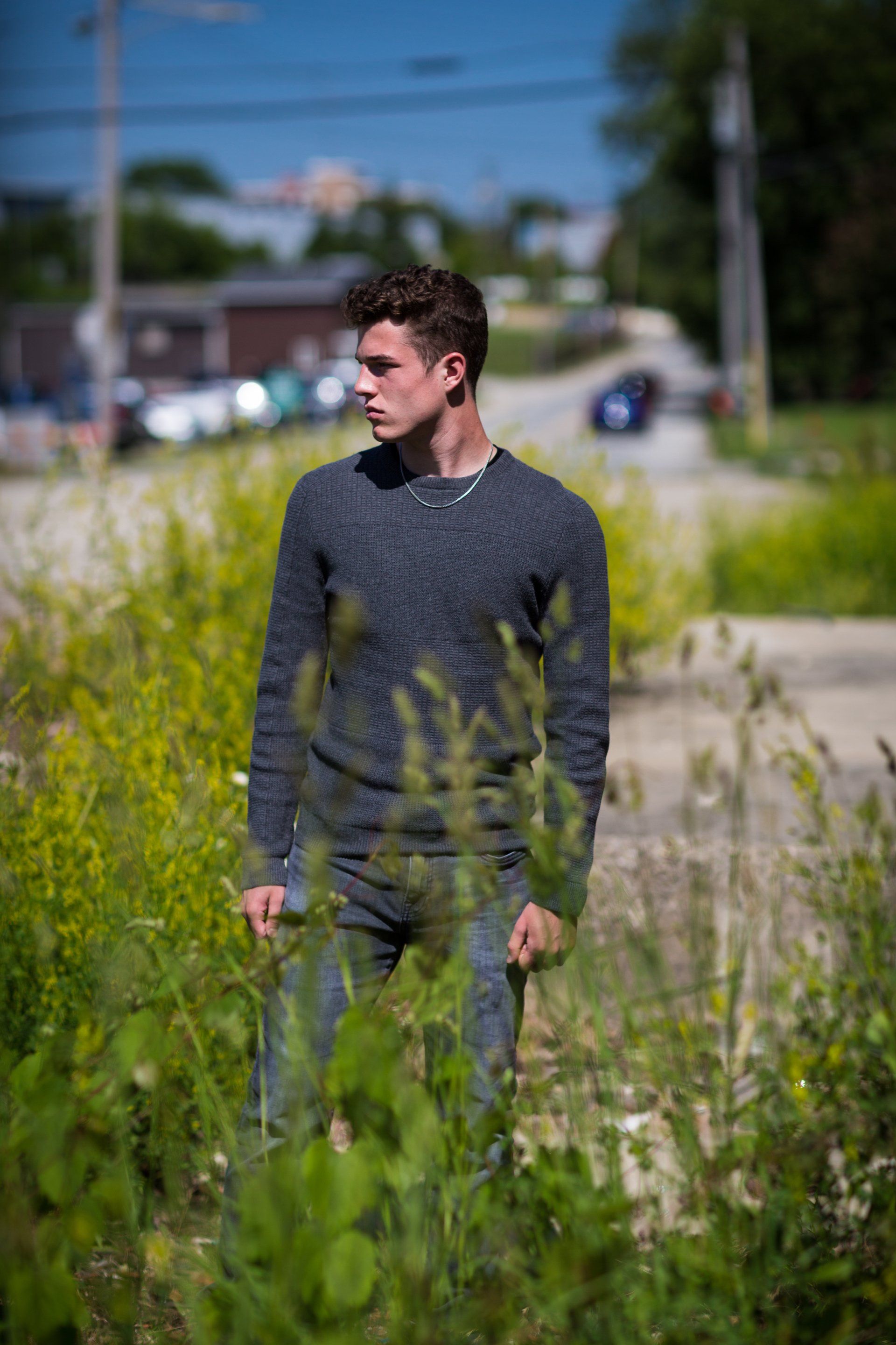 A young man is standing in a field of tall grass.