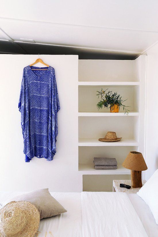 Une robe bleue est accrochée au mur à côté d'un lit.