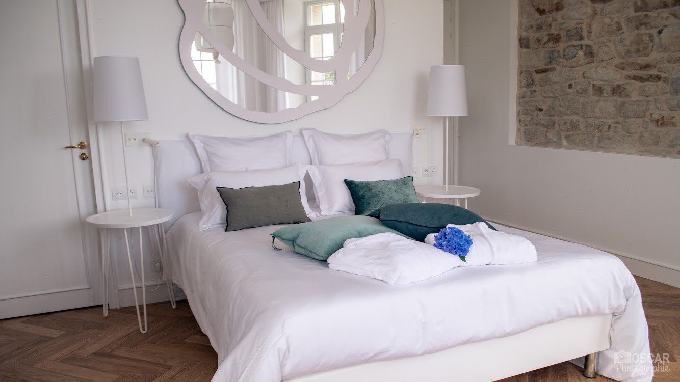 Une chambre avec un grand lit et un miroir au mur.