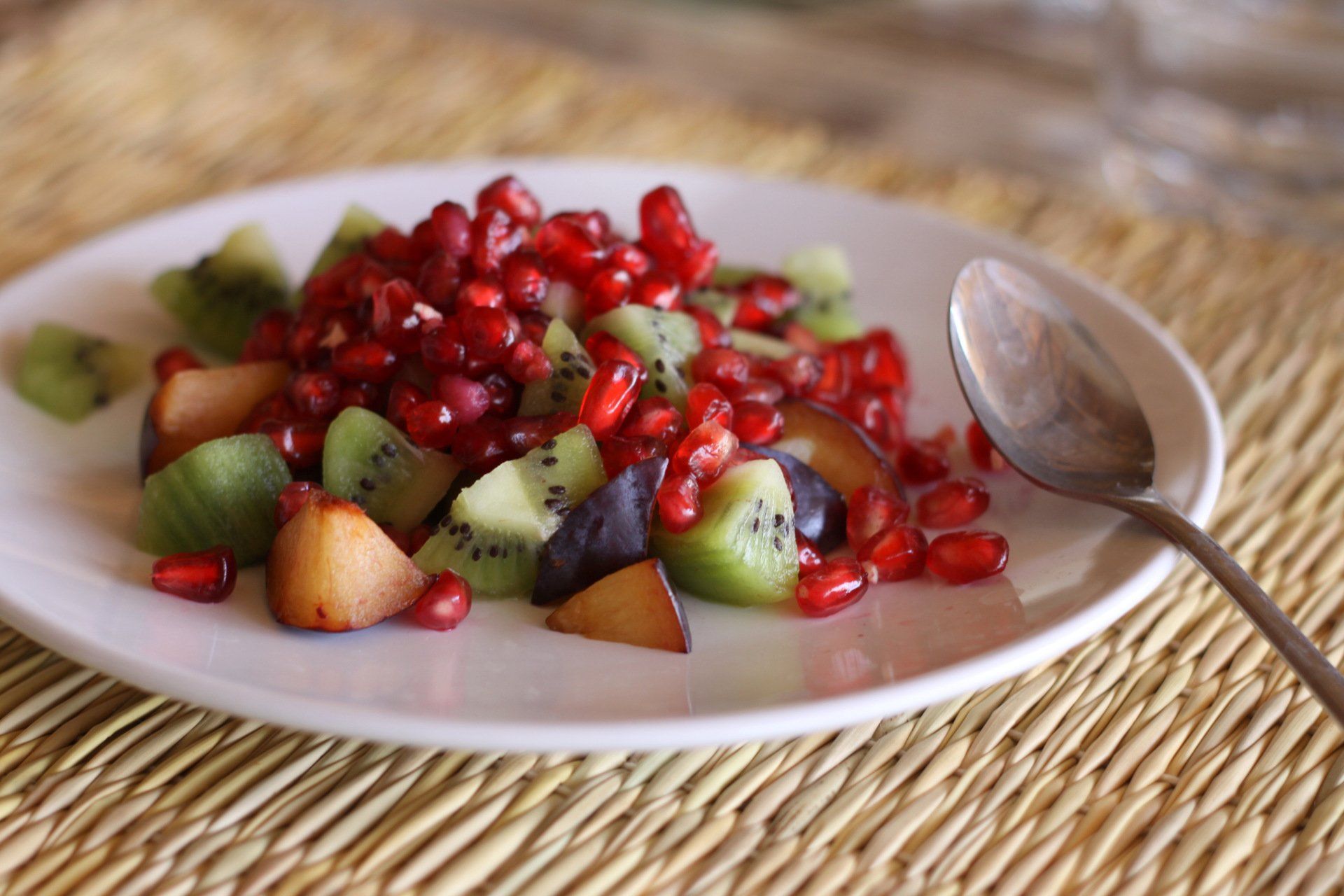 Une assiette blanche garnie de fruits et d'une cuillère sur une table.