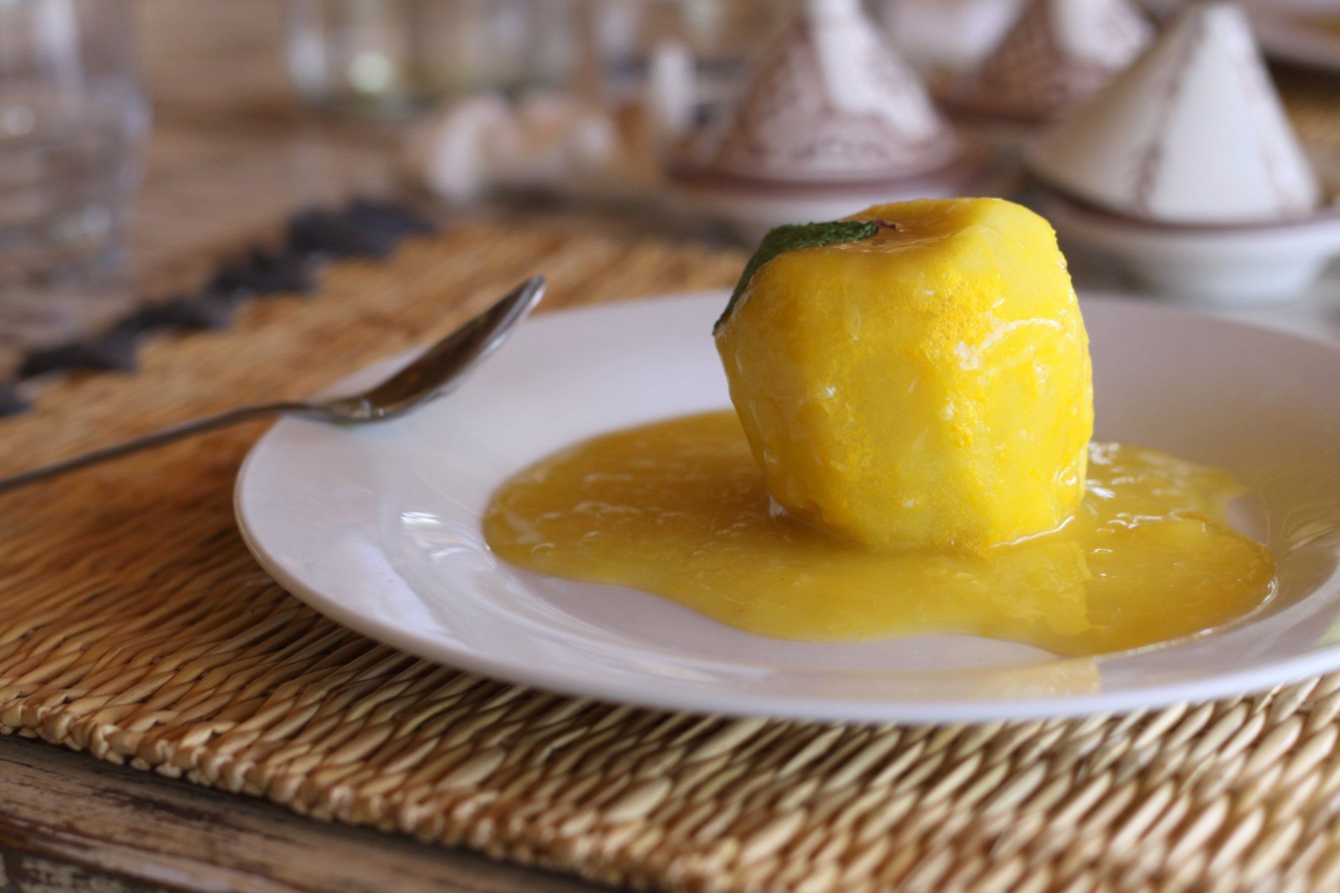 Une assiette blanche garnie d'une sauce jaune et d'un morceau de fruit.