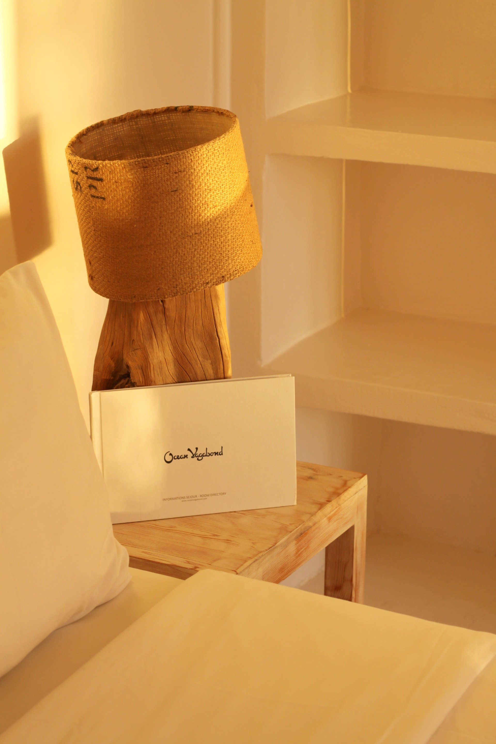 Une lampe est posée sur une table en bois à côté d'un lit